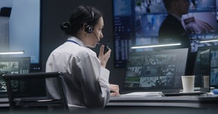 Woman wearing a headset facing a computer and speaking into a microphone