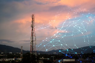 A cellular tower in a cityscape at dusk